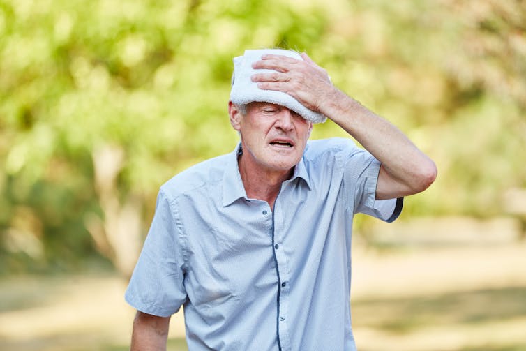 Older man cools his forehead with a facewasher