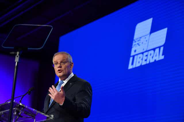 Former Australian Prime Minister Scott Morrison on stage in front of the Liberal Party logo