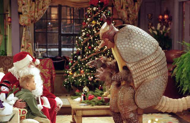 A man dressed as an Armadillo speks to a child sitting with Santa 