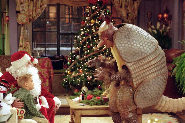 A man dressed as an Armadillo speks to a child sitting with Santa