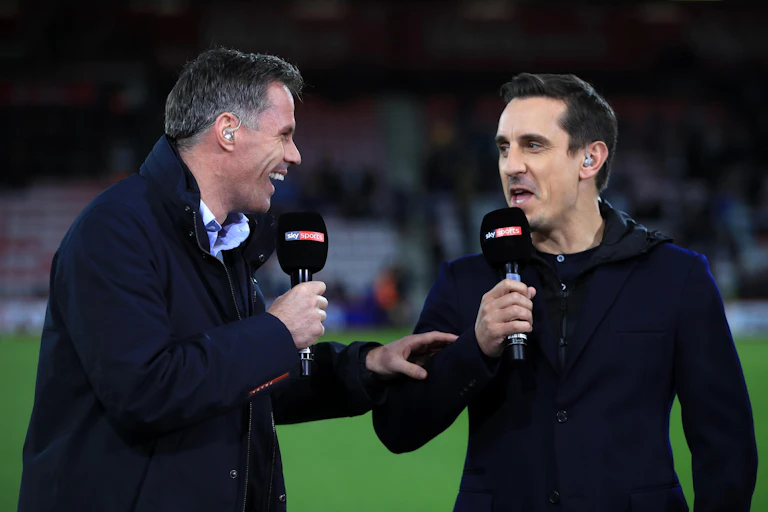 Two sports commentators speaking on a pitch.