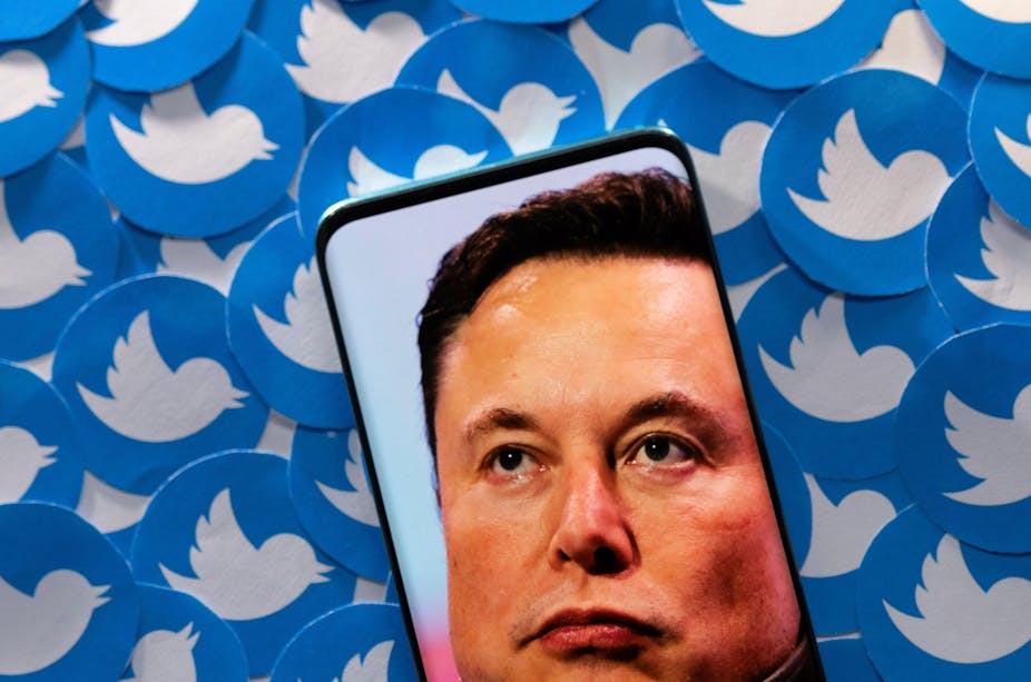 An image of Elon Musk is seen on smartphone placed on printed Twitter logos in this picture illustration.