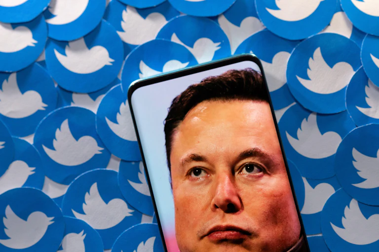 An image of Elon Musk is seen on smartphone placed on printed Twitter logos in this picture illustration.