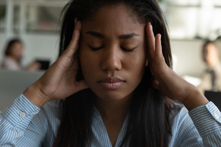 A woman holding her head in pain due to a headache.