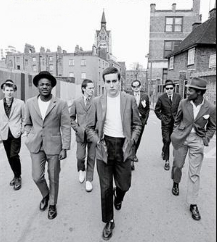 A group of young men, black and white walking along a street.