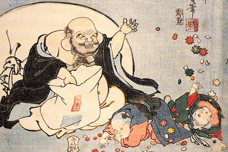 A man throws gifts to children lying on the ground in front of him.
