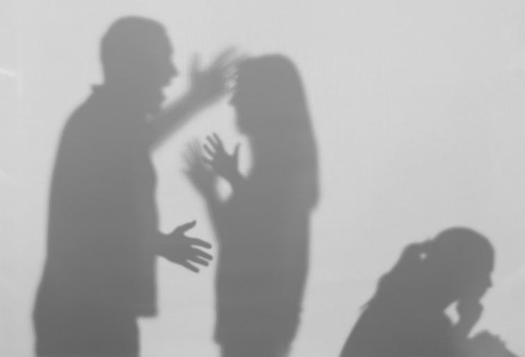 An image of shadows on a wall showing a man and woman arguing which a child sits nearby.