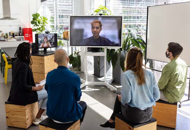 People in office meeting with people on screen