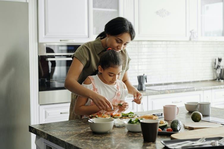 Mother helps child prepare vegetables