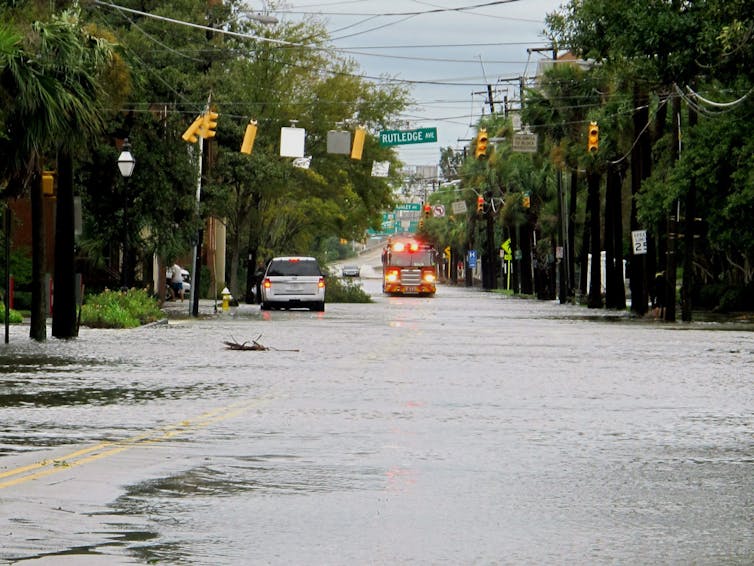 A firetruck drives through a flooded street.