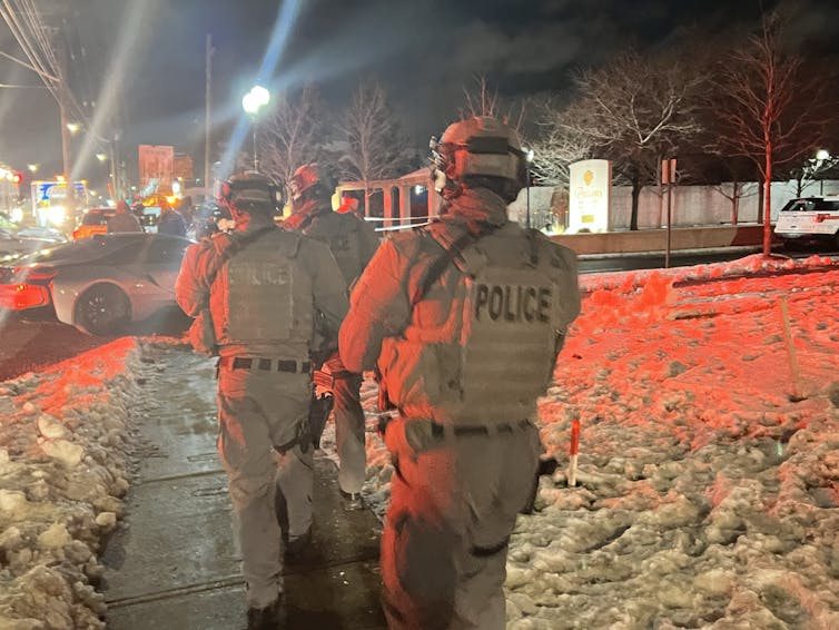 police in tactical gear lit by red police car lights