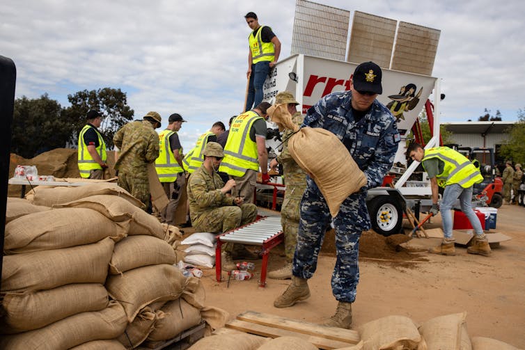 Defence force personnel move sandbags