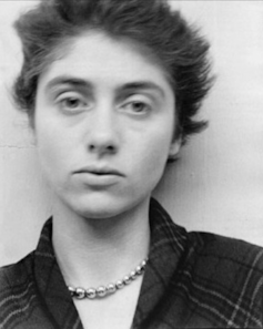 A black and white headshot of a young woman with a necklace and plaid dress – the photographer Diane Arbus.
