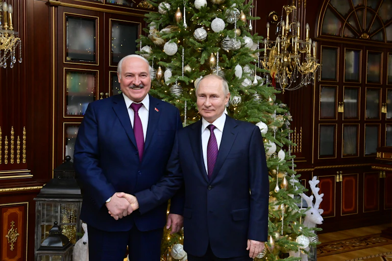 Belarus president Alexander Lukashenko shakes hands with Russian president Vladimir Putin in front of a Christmas tree