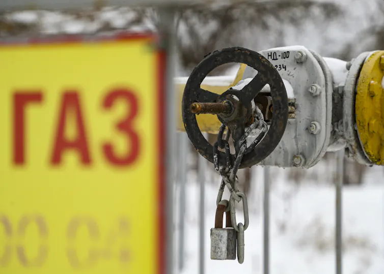 A pipe valve with padlock and chain hanging from it.