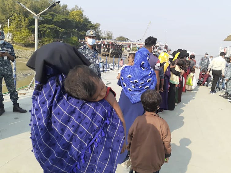 A woman stands in a queue carrying a baby.