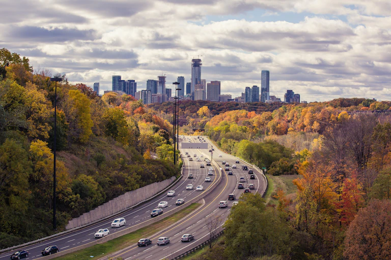 A highway with greenery on both sides leading up to a city
