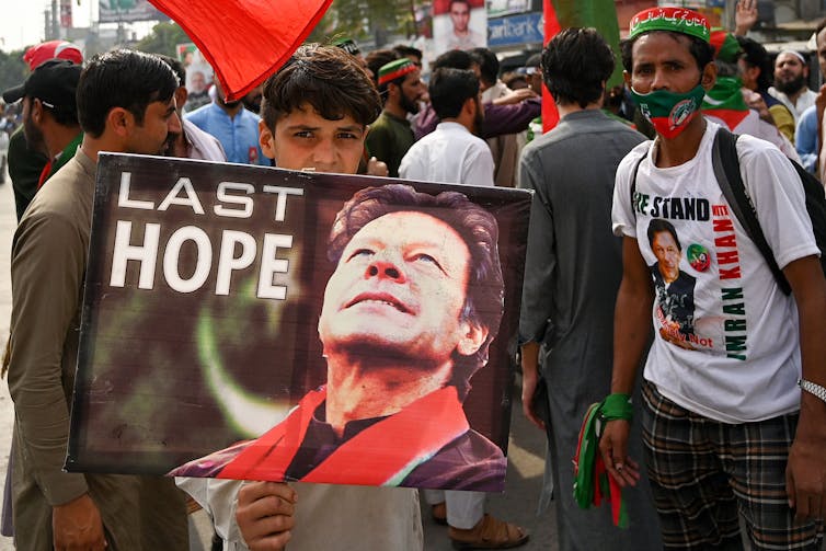 A man holds a poster depicting Imran Khan next to the words 'Last Hope'
