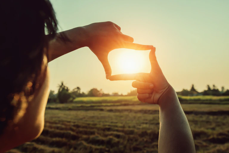 A pair of hands framing the setting sun