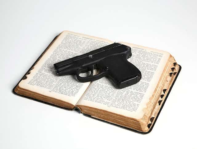 A pistol rests on an open Bible.