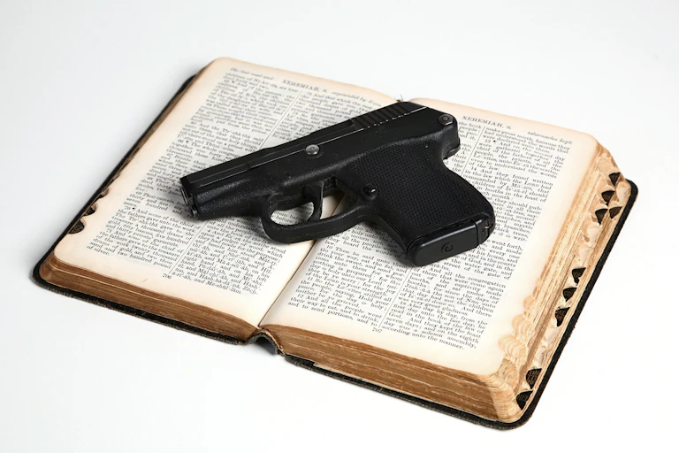 A pistol rests on an open Bible.