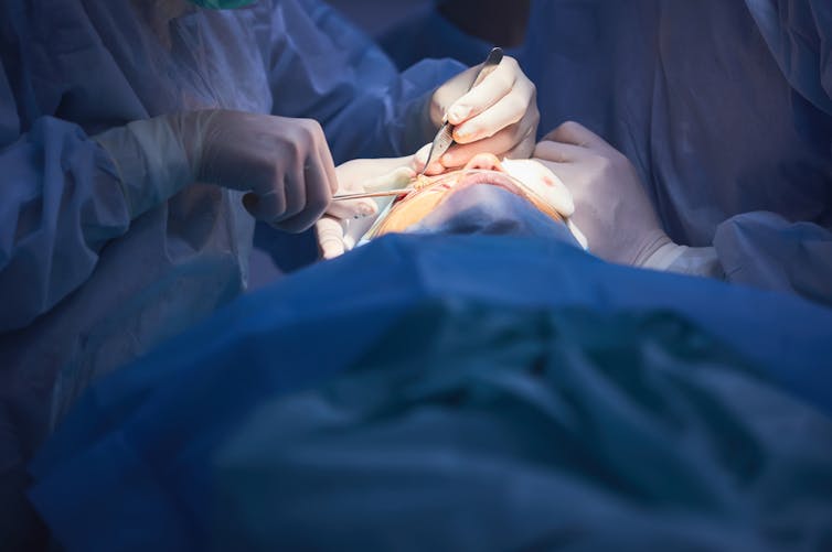 Surgeon with scalpel performing cosmetic surgery to face