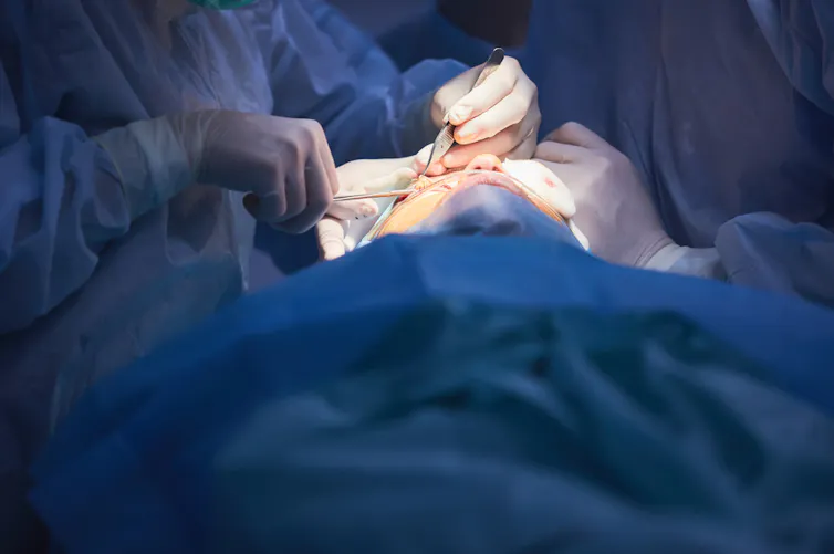 Surgeon with scalpel performing cosmetic surgery to face