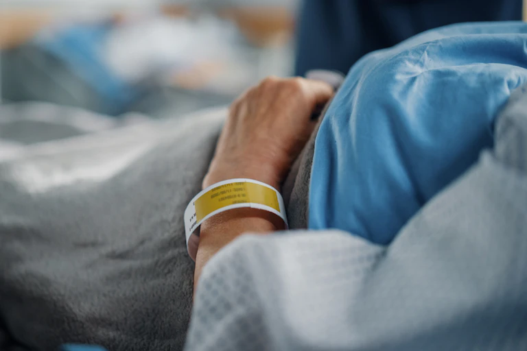 Person with hospital bracelet lying in hospital bed