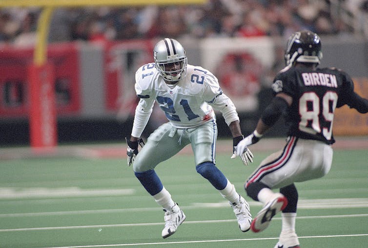 Two football players anticipate a pass.