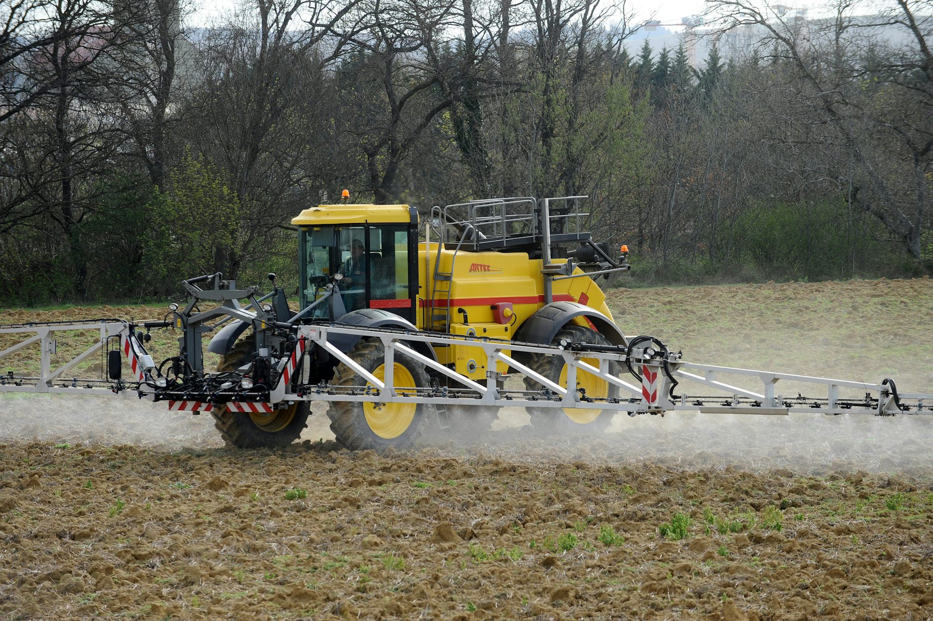 Un engin agricole asperge un champ avec des pesticides