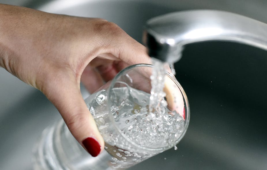 Une personne prenant de l'eau du robinet dans un verre