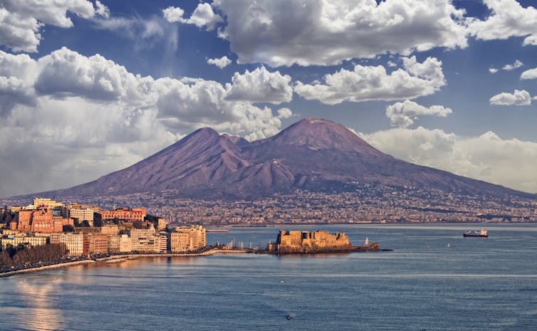 A photograph of the city of Naples, Italy, with Mount Vesuvius in the background.