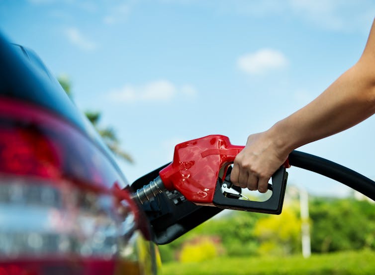 Hand refilling the car with fuel.