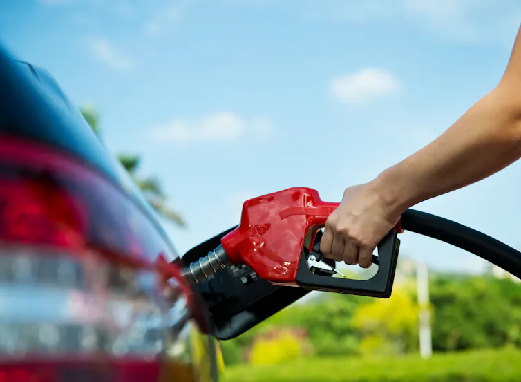 Hand refilling the car with fuel.