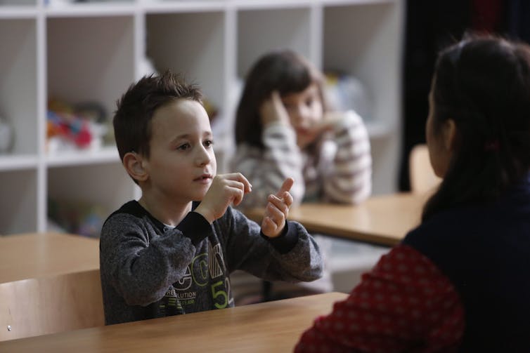 A child seen practising signing in a classroom.