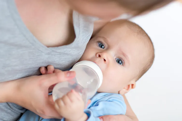A mother bottle feeding her baby.