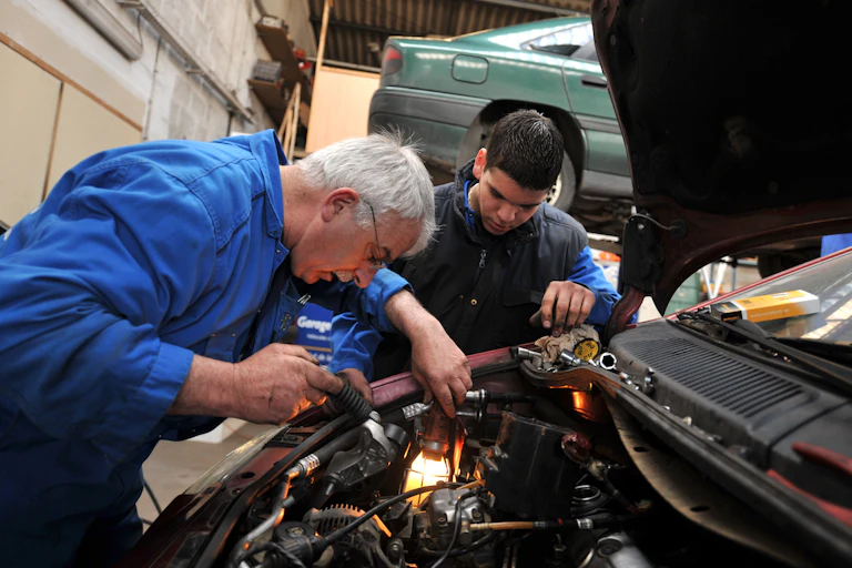 Une personne senior au travail dans un garage automobile.