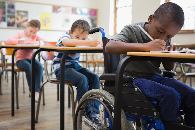 Students seen sitting in a classroom, one who is a wheelchair user.