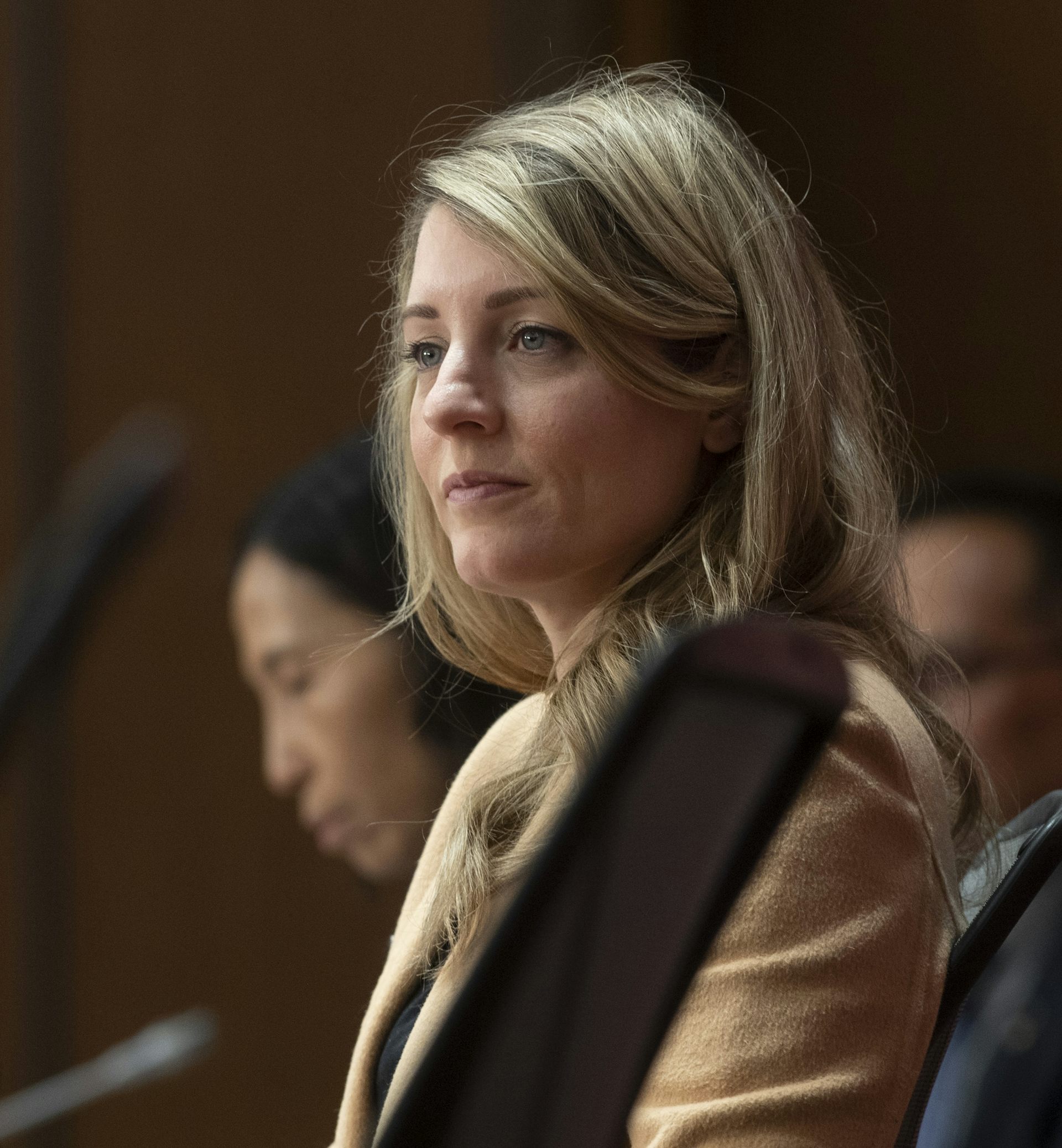 A photo of a woman with blond hair wearing a beige coat.