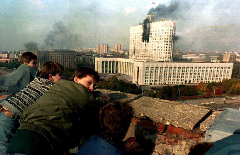 Des jeunes gens regardent le bâtiment du Parlement russe à Moscou en proie aux flammes
