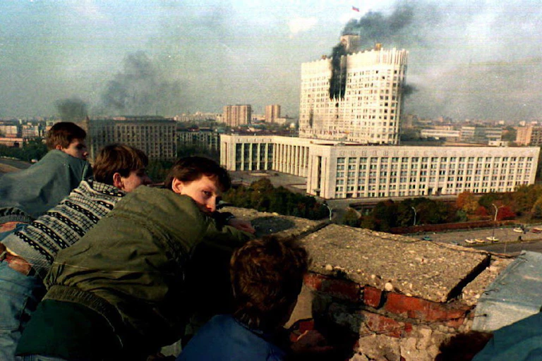 Des jeunes gens regardent le bâtiment du Parlement russe à Moscou en proie aux flammes