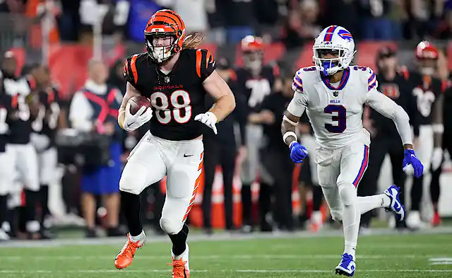 A football player chasing another player who has the ball.