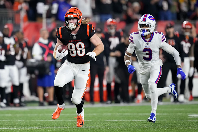 A football player chasing another player who has the ball.