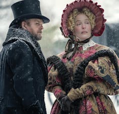Gillian Anderson and Toby Jones stand in the snow wearing extravagant, overly ornate Victorian clothing.