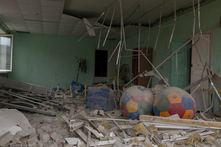 Metal, ceiling tiles and dust are strewn across a ruined room.