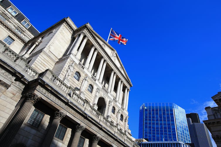 A union jack, British flag, flies above the bank of england building in London.