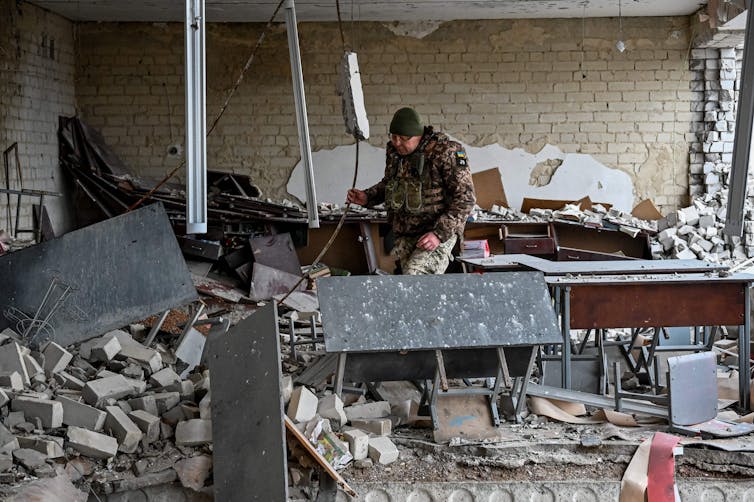 A Ukrainian soldier inspects a room in a damaged school building near Kupiansk, Kharkiv region on December 15, 2022.
