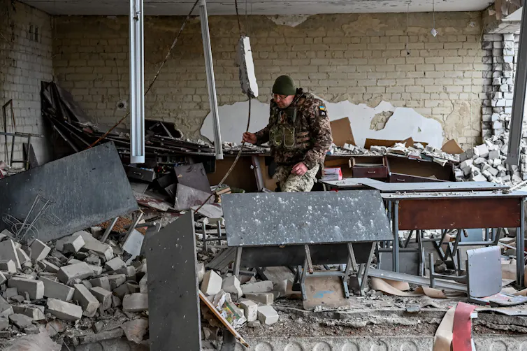 A Ukrainian soldier inspects a room in a damaged school building near Kupiansk, Kharkiv region on December 15, 2022.