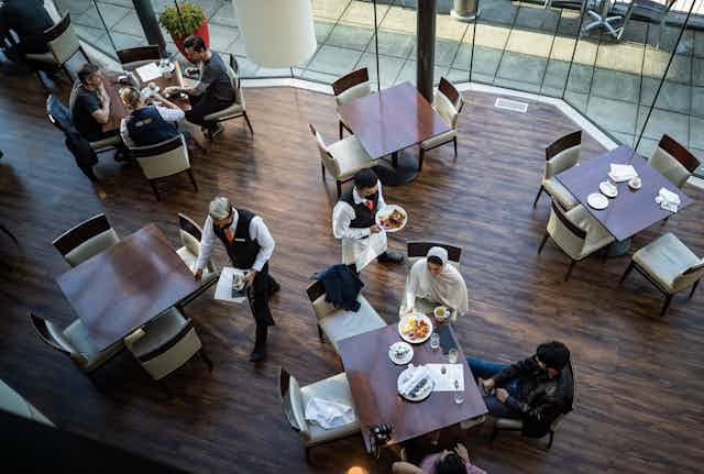A bird's eye view of a server bringing food to a table of people in a restaurant