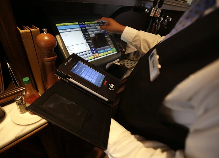 A waiter processes a dinner tab with a credit card processing device